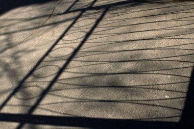 Asfalttaki çitin geometrik gölgeleri