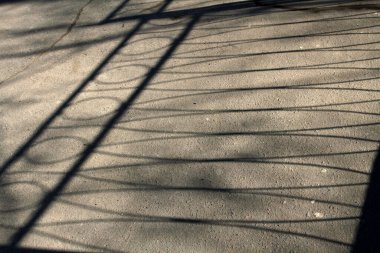 Asfalttaki çitin geometrik gölgeleri