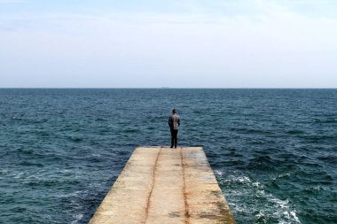 İskelenin sonunda bir adam duruyor.