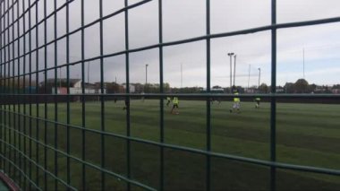 Astroturf 'ta oynanan futbol, tel örgüden izleniyor.