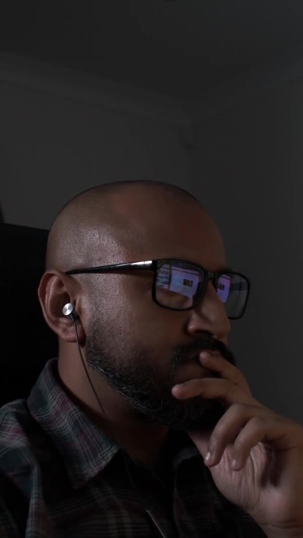 光秃秃的男性戴着眼镜 在服务台的耳机上听音乐 垂直视频 锁定关闭 — 图库视频影像