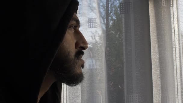 Man Dragen Hoodie Binnen Kijken Pensively Out Window Tijdens Lockdown — Stockvideo