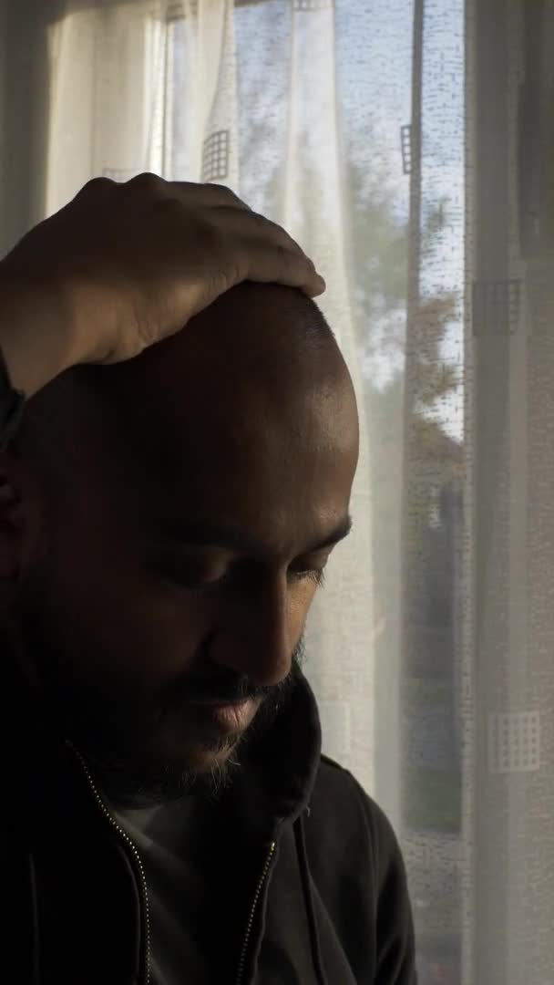 Adult Male Stroking Bald Head Indoors Window Lockdown Vertical Video — Vídeos de Stock