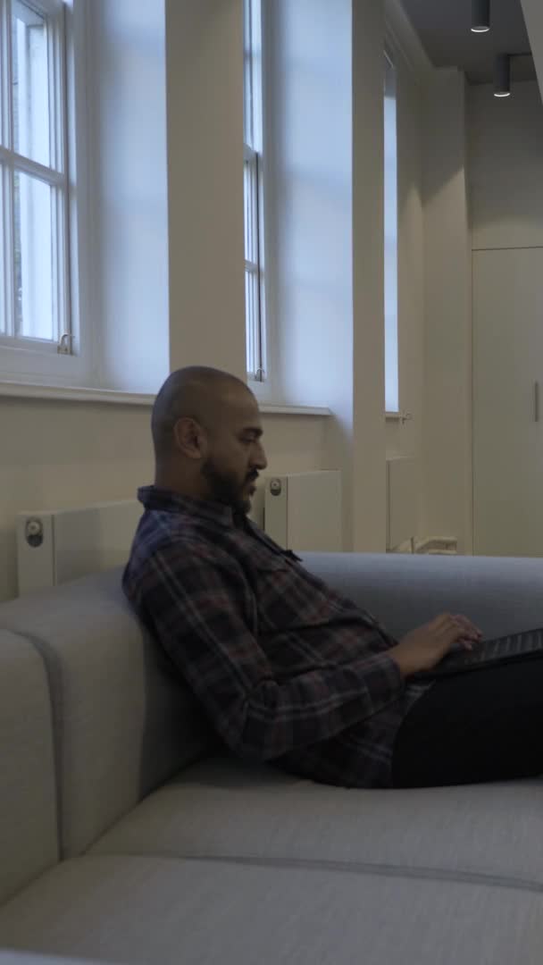 Asian Masculino Usando Laptop Sentado Sofá Escritório Vídeo Vertical Trancado — Vídeo de Stock
