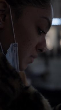 Gece Bokeh Light 'ın telefonuna bakarken genç bir kadının yüzüne yakından bakın. Dikey Video
