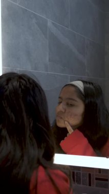 Genç Bayan Genç Banyodaki Aynada Sivilceleri Kontrol Ediyor. Dikey Video, Kilitli 