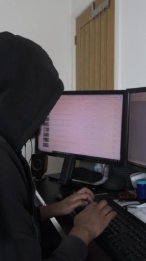 İçişleri Bakanlığı 'nda çift monitörlerin önünde kapüşonlu erkek yazı yazıyor. Dikey Video, Kilitli