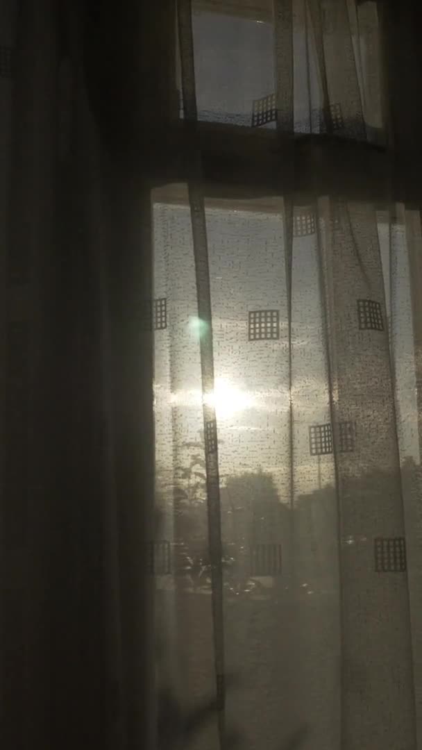 カーテンの窓の外の夕日 垂直ビデオ スロートラック右 — ストック動画