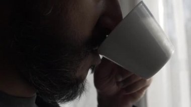 Etnik Azınlık Sakallı Erkek Kupa 'dan İçiyor Perdelerin Yanında. Kapat, Kapalı