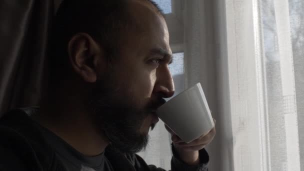Ethnic Minority Bearded Adult Male Drinking Cup Looking Out Curtains — Stock Video