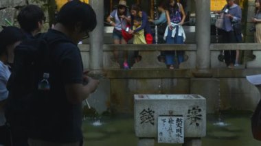 Kyoto 'daki Kiyomizu-Dera Tapınağı' ndaki Otowa Şelalesi 'nde su toplayan turistler. Kilitli 