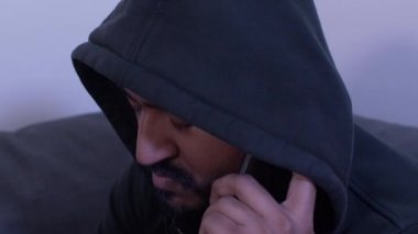 Cep telefonunda konuşan kapüşonlu bir erkek. Parallaks Sağdan Sola Kaydır, Kapat