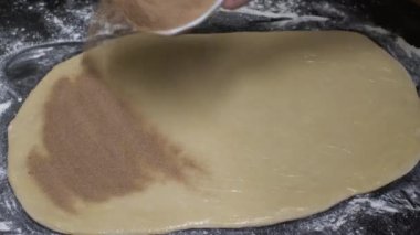 Tarçın, düzleştirilmiş hamur hamuru üzerine serpiştiriliyor. Kilitli