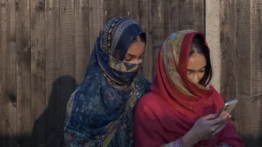 Shalwar Kameez 'de cep telefonu kullanan iki genç Müslüman kadın. Kilitli