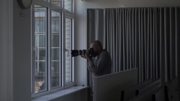 窓から写真を撮るために望遠レンズを使用して私立男性探偵 ロックオフ — ストック動画