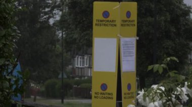 Yellow Temporary Restricting No Parking Signs On Lamppost On Road In Harrow, London. Locked Off