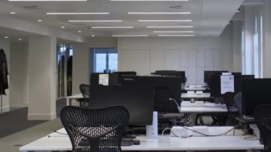 Londra 'daki açık planlı ofis binasında boş masalar ve sandalyeler. Yavaşça Sağa