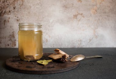 Cam bir kavanoz taze et kemiği çorbası. Yanında da eski bir kaşık ve yuvarlak bir baharat var. Vitamin, kolajen ve amino asit açısından zengin sağlıklı bir diyet. Boşluğu kopyala.