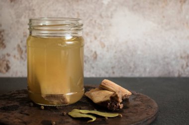 Koyu arkaplanda baharatlı taze et kemiği çorbası ile cam kavanoz. Vitamin, kolajen ve amino asit açısından zengin sağlıklı yiyecek kavramı. Uzayı kopyala..