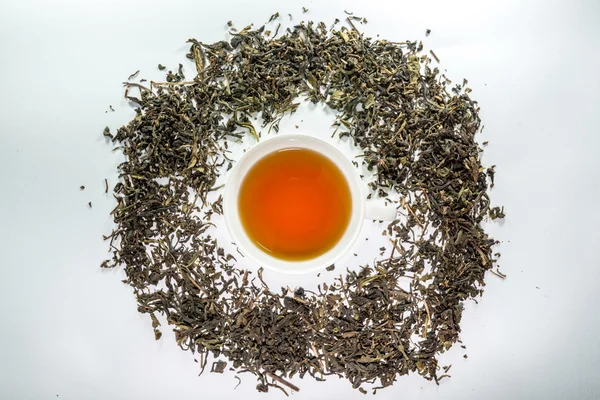 En kopp te i mitten av te blad — Stockfoto
