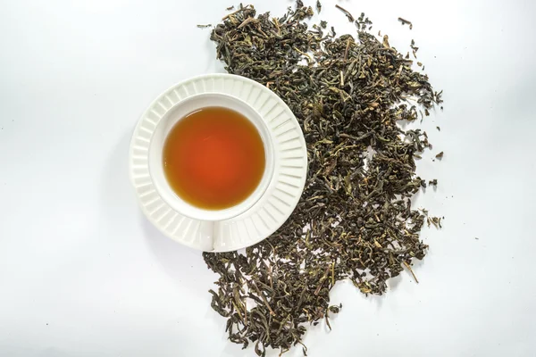 Белая чашка чая и сухой чайный лист — стоковое фото