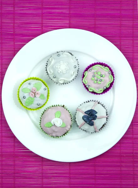 Cinq muffins décorés sur un napperon en bois et rose — Photo