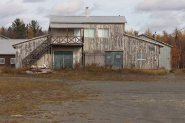 Gri metal duvarları ve kırmızı metal çatısı olan terk edilmiş bir ahır.