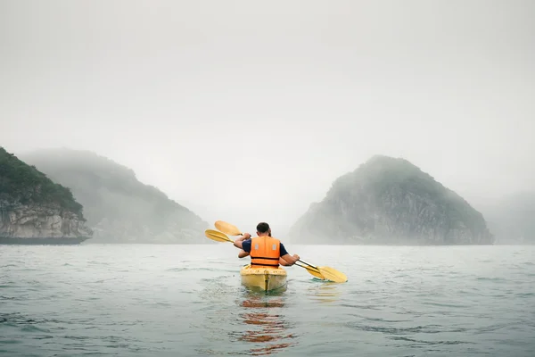 Couple paddling the kayak in mist weather — Stock Photo, Image