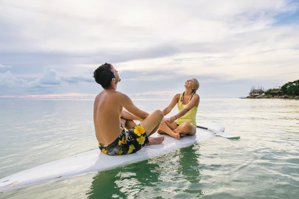 Lyckliga par surfa tillsammans paddla ombord vid solnedgången — Stockfoto