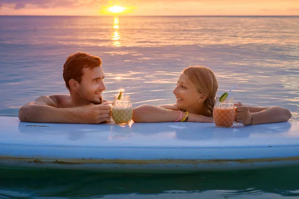 Šťastný pár relaxovat na palubě pádlo při západu slunce — Stock fotografie