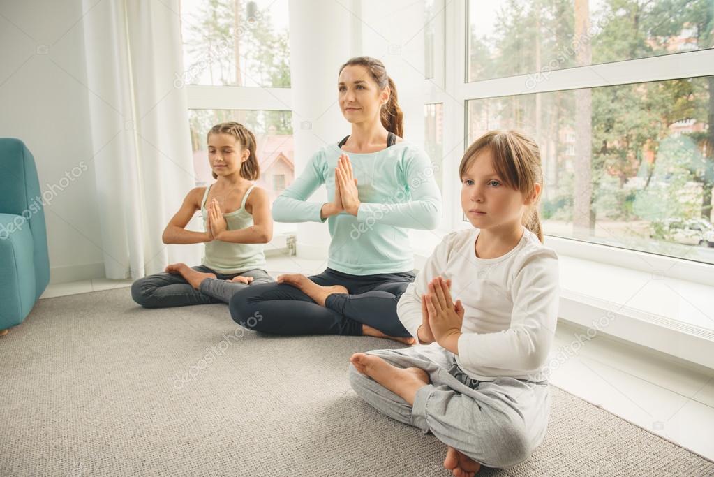 Young mother with children meditating at home