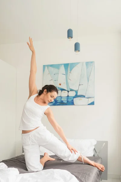 Donna che fa esercizi di yoga a letto — Foto Stock