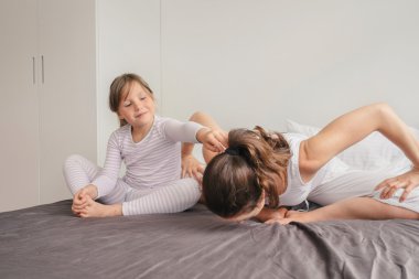 Anne ile kızı yatakta yoga egzersiz yaparak