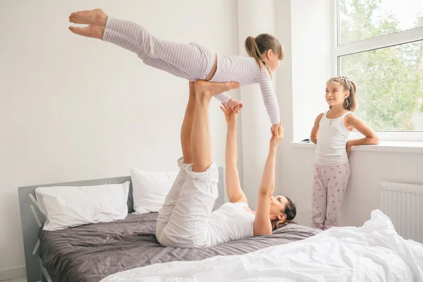 Μητέρα με τα παιδιά που κάνουν γιόγκα άσκηση στο κρεβάτι — Φωτογραφία Αρχείου