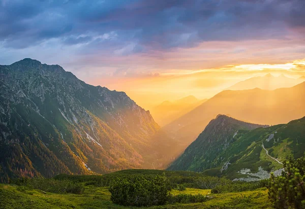 Pôr do sol dourado com raios de sol em grande paisagem montanhosa — Fotografia de Stock