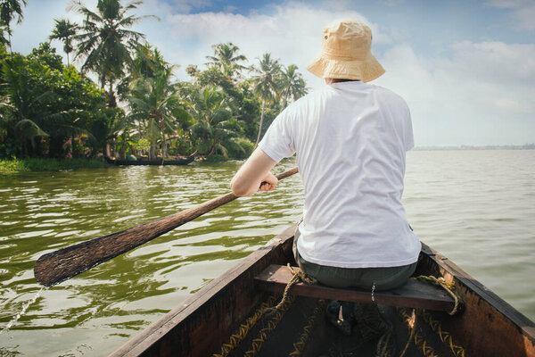 Tourist man floating on Alleppey backwaters and enjoying beautiful view