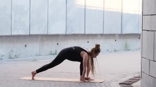 Jonge vrouw in yoga geconfronteerd hond pose — Stockvideo