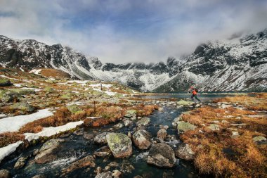 Kayaların arasında yüksek Tatras göle üstünden atlayarak bir adam