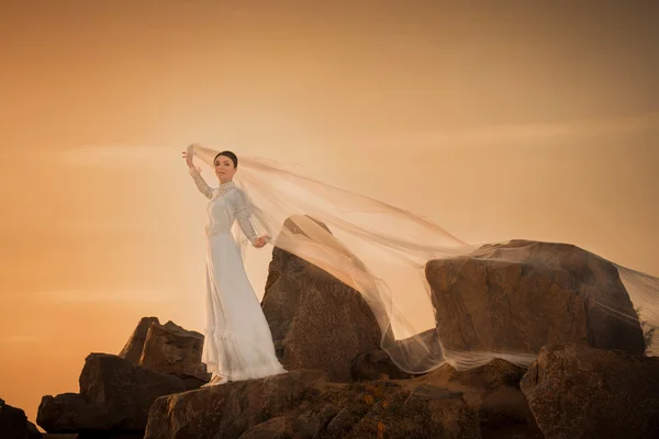 Mulher bonita segurando cachecol branco no fundo por do sol — Fotografia de Stock