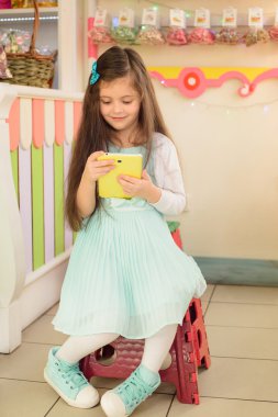 Şekerci dükkanında tablet bilgisayar kullanan mutlu küçük kız