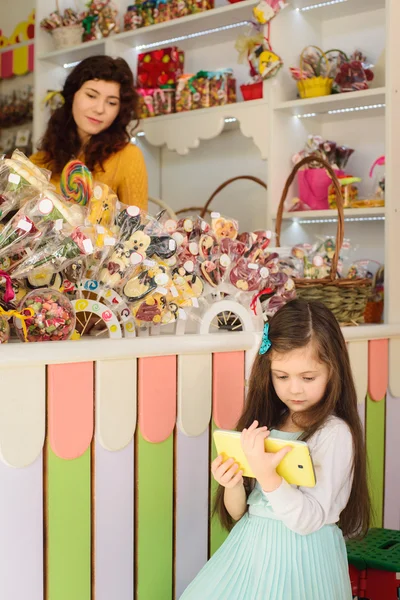 Little girl using tablet computer in candy store — Stock Photo, Image