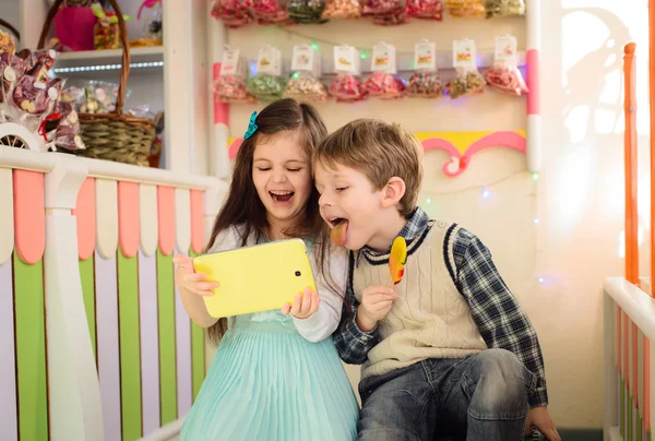 Enfants heureux jouant tablette dans un magasin de bonbons Images De Stock Libres De Droits