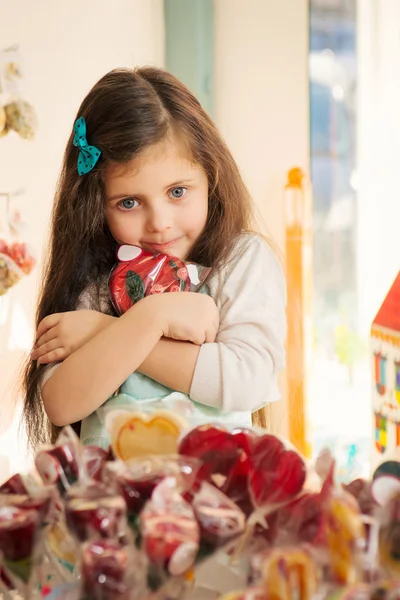 Greed  little girl with lollipop in candy store — Stock Photo, Image