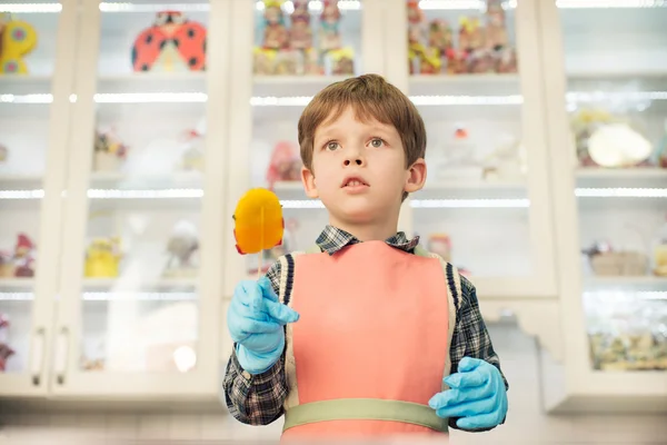 Boy standing at the kitchen with lollipop — Stock Photo, Image