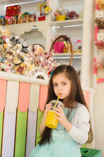 Little girl drinking orange juice through straw — Stock Photo, Image