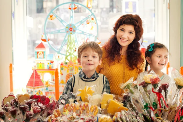 Mother with happy children in the candy store — Stock Photo, Image