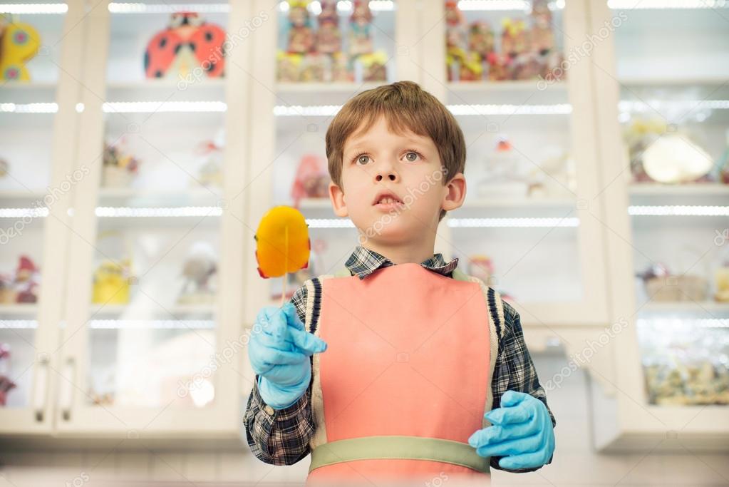 Boy standing at the kitchen with lollipop