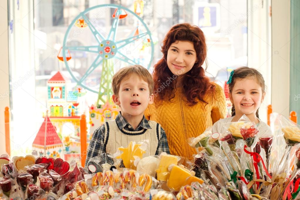 Mother with happy children in the candy store