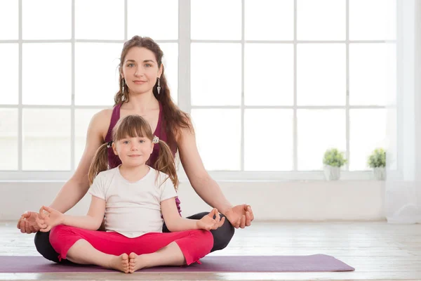 Jeune mère et sa fille assis en position lotus — Photo