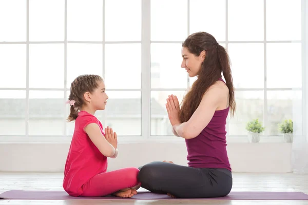 Ung mor och dotter gör yoga övning — Stockfoto